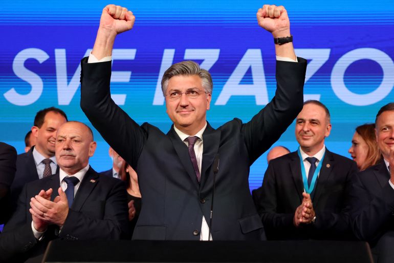 Croatian Prime Minister Andrej Plenkovic. He is standing on. stage with his arms aloft and his fists clenched. He looks happy. People behind him are clapping.