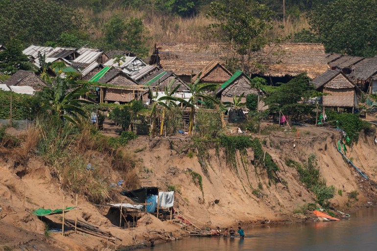 A view of a camp for people displaced by the fighting in Myanmar. It's on the banks of the Moei river, which separates Myanmar from Thailand. The buildings are of bamboo and palm.