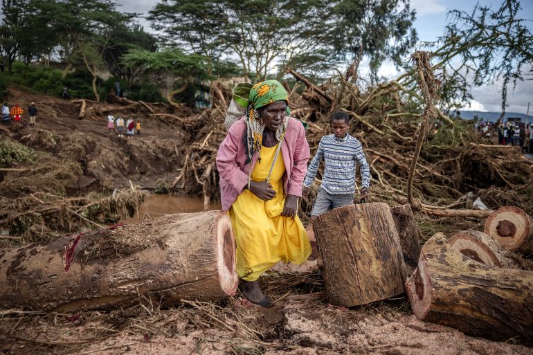 A woman walks in an area full of damaged trees, mud and debris carried by water following flash floods and landslides in Mai Mahiu, on April 30, 2024. At least 48 people died on April 29, 2024 when a dam burst its bank near a town in Kenya's Rift Valley, President of Kenya William Ruto said on April 30, 2024. The disaster raises the total death toll over the March-May wet season in Kenya to more than 170 as heavier than usual rainfall pounds East Africa, compounded by the El Nino weather pattern. (Photo by LUIS TATO / AFP)