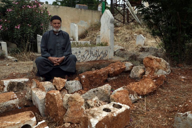 Mohammed Hassan Masto sits next to a grave in Syria