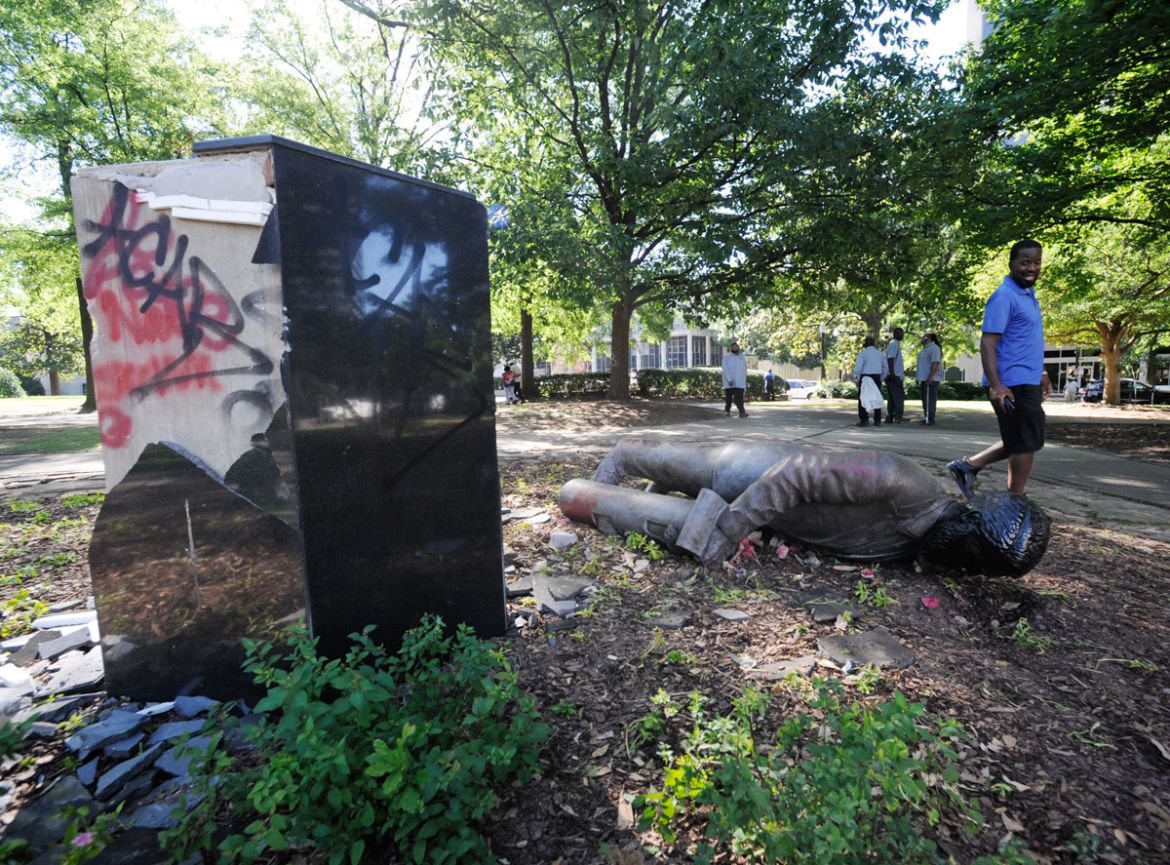 ADDS INFORMATION ON STATUE - An unidentified man walks past a toppled statue of Charles Linn, a city founder who was in the Confederate Navy, in Birmingham, Ala., on Monday, June 1, 2020, following a