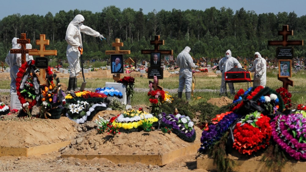 Grave diggers wearing personal protective equipment (PPE) bury a person, who presumably died of the coronavirus disease (COVID-19), in the special purpose section of a 