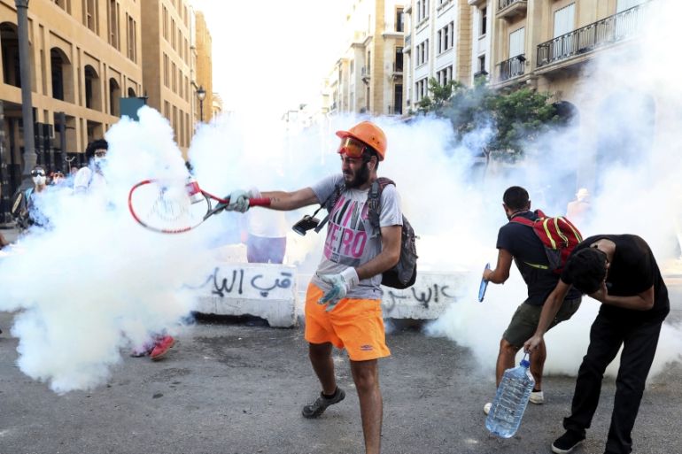 An anti-government protester uses a a tennis racket to hit back a tear gas canister towards at riot policemen during a protest following last Tuesday''s massive explosion which devastated Beirut, Leban