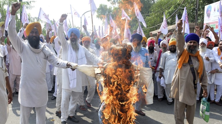 Farmers shout slogans as burn an effigy of Indian Prime Minister Narendra Modi and Union Agriculture Minister Narendra Singh Tomar, following the passing of agriculture bills in the Lok Sabha (lower h