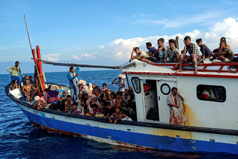 Rohingya refugees packed onto the deck of a wood fishing boat. Some are sitting on top of the wheelhouse.