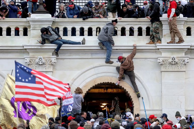 A mob of supporters of US President Donald Trump fight with members of law enforcement at a door they broke open as they storm the US Capitol Building in Washington on January 6, 2021