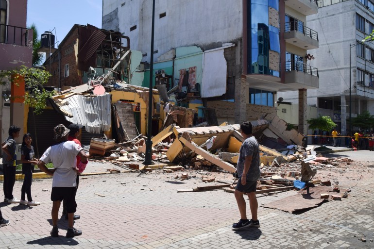 Residents look at a building that collapsed after an earthquake shook Machala, Ecuador, Saturday, March 18, 2023. 