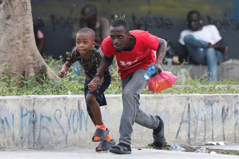 People take cover from gunfire near the National Palace, in Port-au-Prince