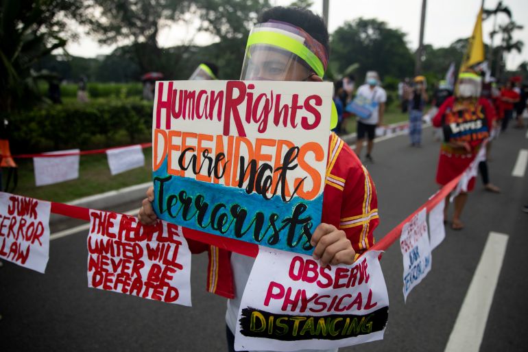 A protester holding up a placard reading 'Human rights defenders are not terrorists' during protests against the anti-terrorism law in Manila in 2020. Other people are walking on the street behind them.