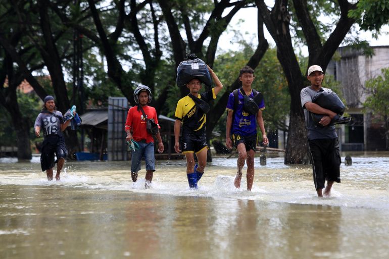 Local residents carry they belongings in a flooded street