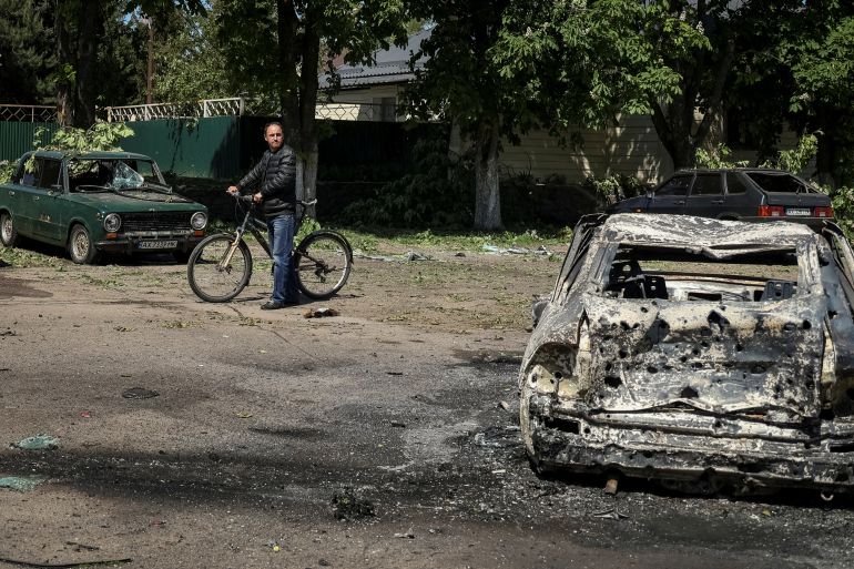 A local resident looks at a destroyed car at a site of a Russian missile strike, amid Russia's attack on Ukraine, in the village of Zolochiv in Kharkiv region, Ukraine May 1, 2024. REUTERS/Sofiia Gatilova
